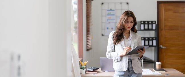 Woman accountant using calculator and digital tablet computer in office, finance and accounting concept.
