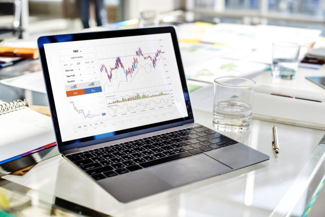 Laptop z wykresami finansowymi na biurku – analiza finansowa, wyniki i inwestycje