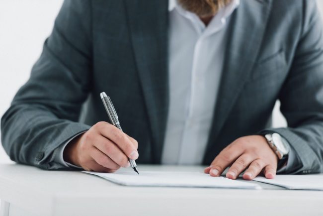 Przedsiębiorca podpisuje umowę i dokumenty firmowe przy biurku