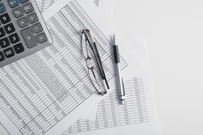 Zestawienia finansowe, kalkulator, okulary i długopis – księgi, bilans i deklaracje podatkowe